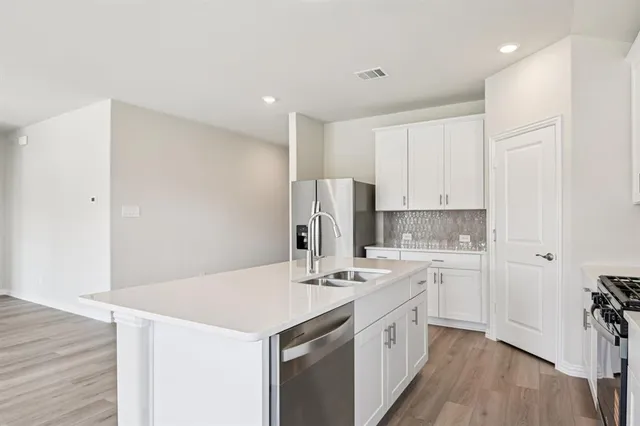a kitchen with a sink a stove a refrigerator and white cabinets
