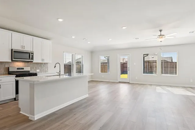 a large kitchen with stainless steel appliances granite countertop a stove a sink dishwasher and a microwave oven with wooden floor