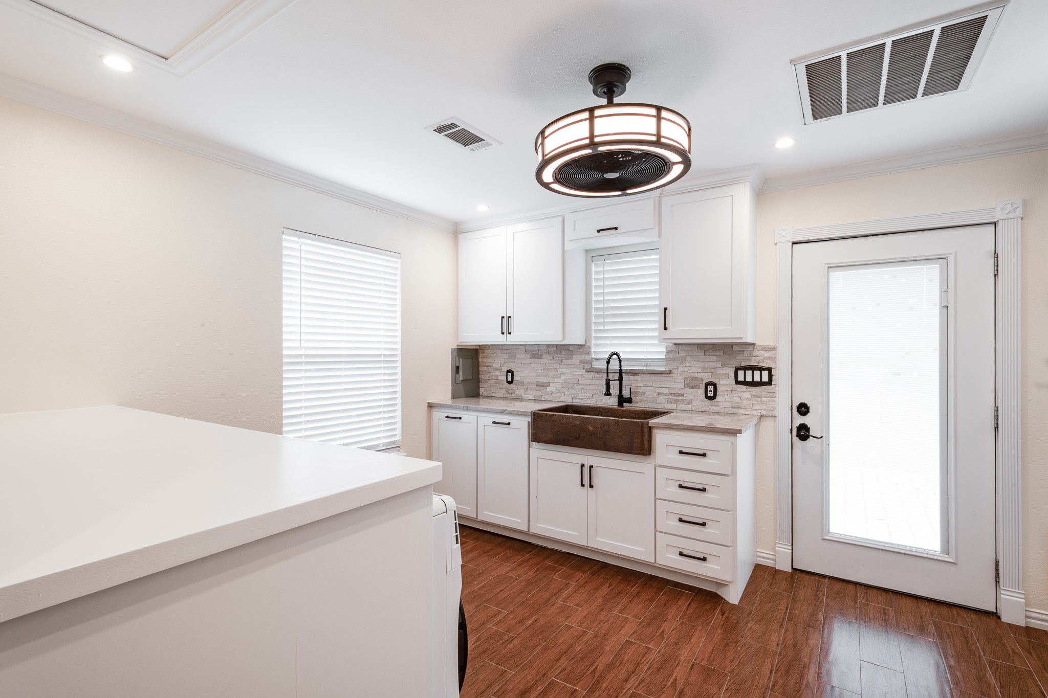 11620 Fostoria Road Cleveland, TX 77328 - Photo 12 of 26 a kitchen with stainless steel appliances a stove a sink and white cabinets with wooden floor next to windows