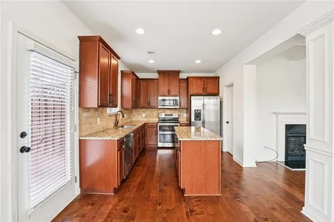 a kitchen with stainless steel appliances granite countertop a sink stove microwave and refrigerator