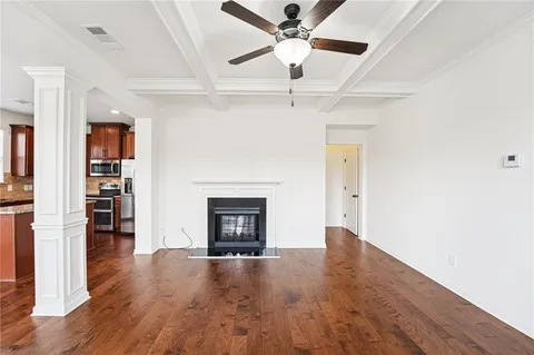 a view of an empty room with chandelier fan and wooden floor