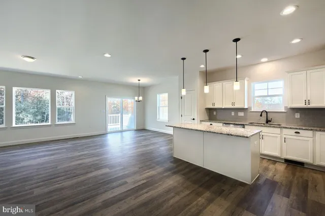 a large kitchen with stainless steel appliances granite countertop a stove a sink and white cabinets with wooden floor next to windows