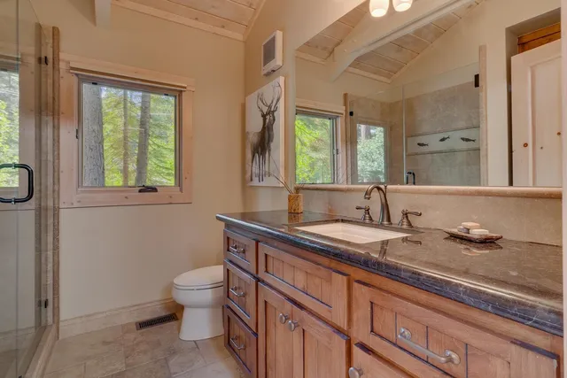 a bathroom with a granite countertop toilet a sink a mirror and a window