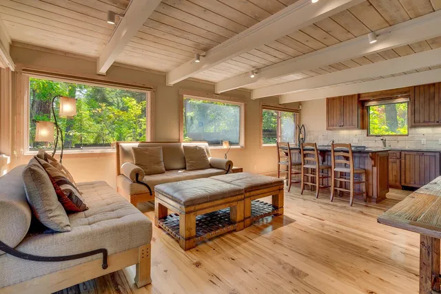a living room with furniture a flat screen tv and floor to ceiling windows