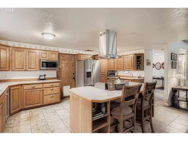 a large kitchen with kitchen island granite countertop a sink counter and chairs