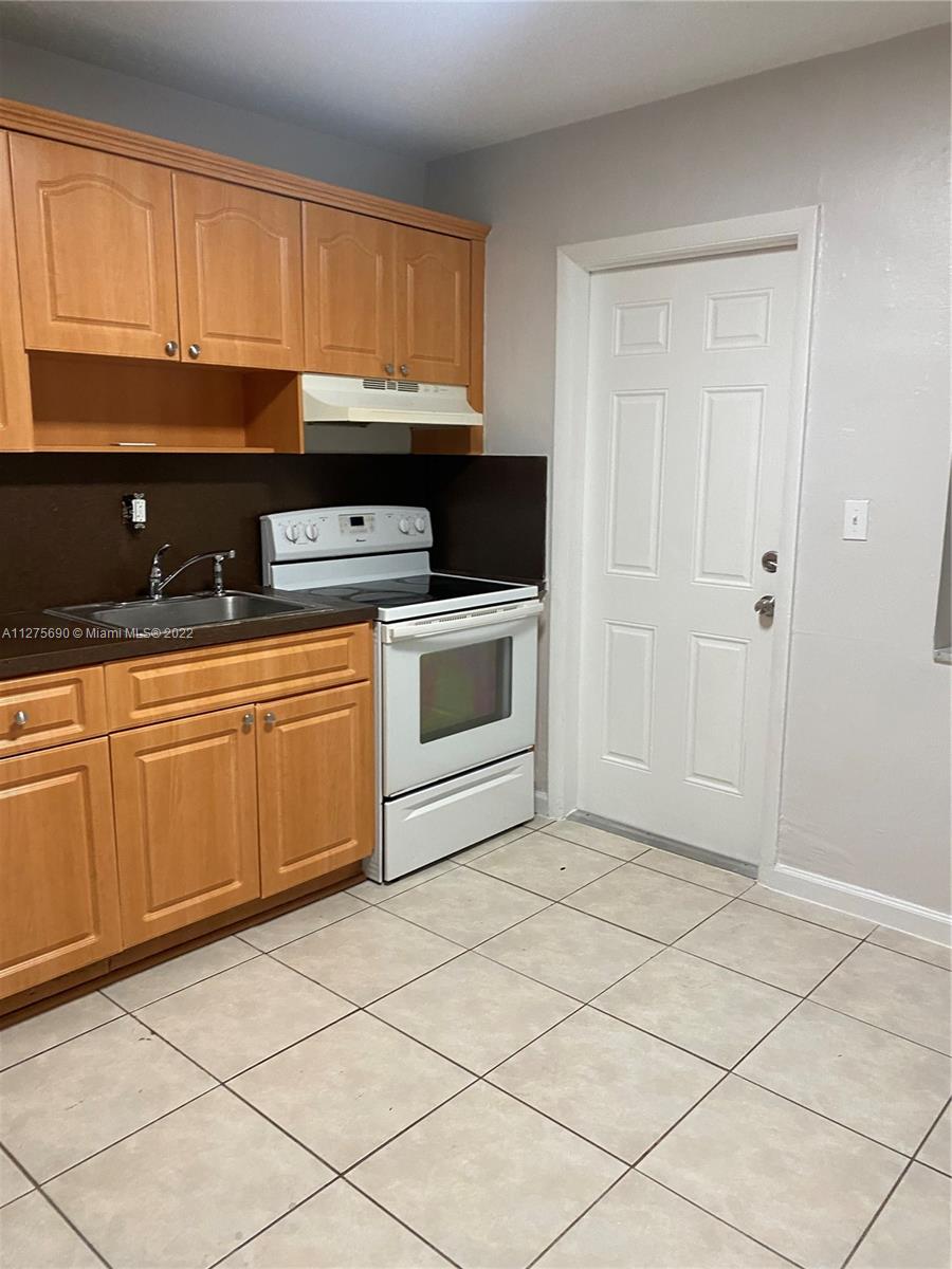 Allapattah Miami, FL 33142 - Photo 19 of 31 a kitchen with granite countertop a sink a stove top oven and cabinets