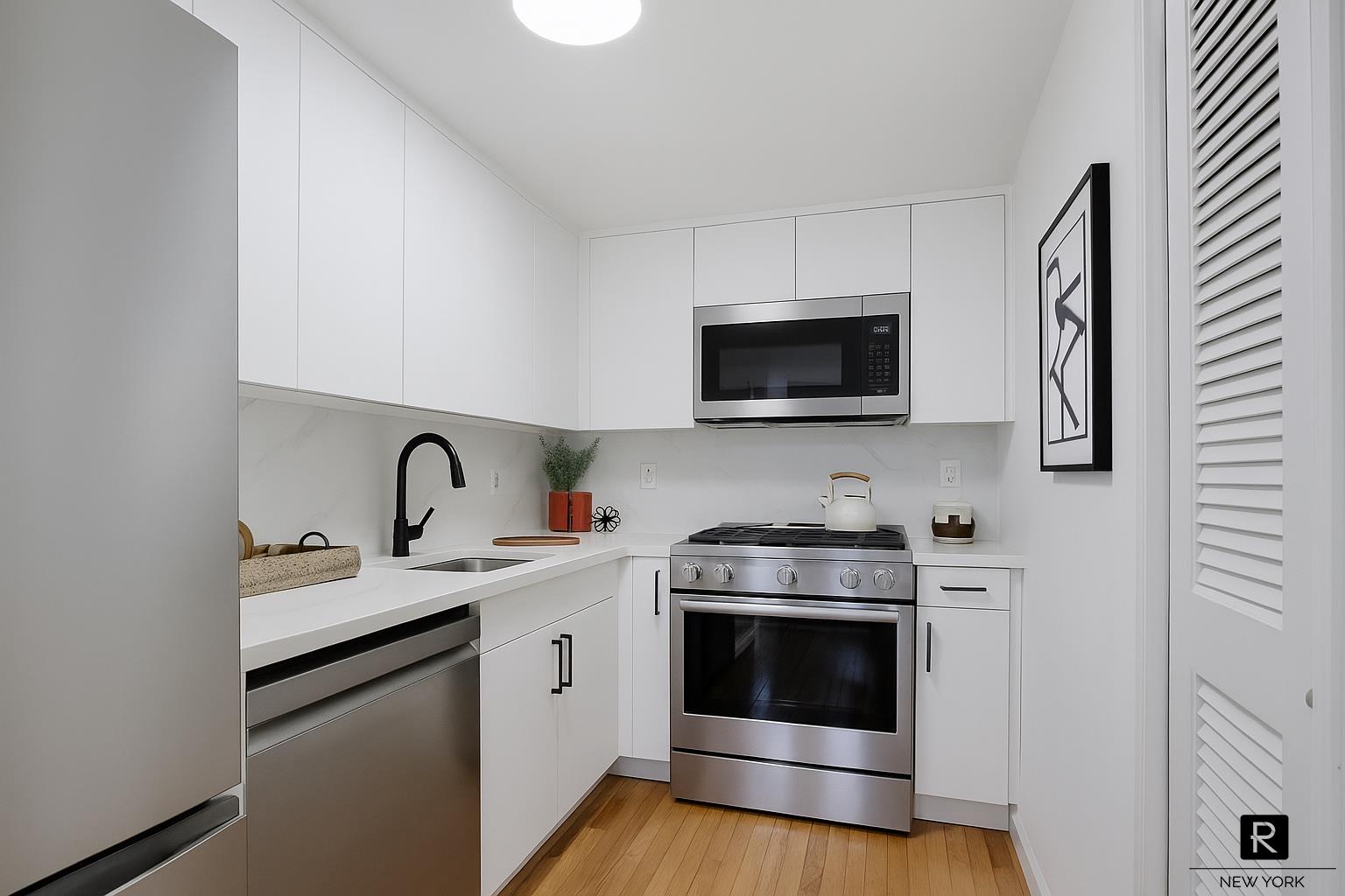 407 East 12th Street, Unit 4FSW Manhattan, NY 10009 - Photo 4 of 16 a kitchen with stainless steel appliances granite countertop a sink a stove a microwave and cabinets