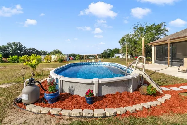 a view of a swimming pool with a patio and a yard