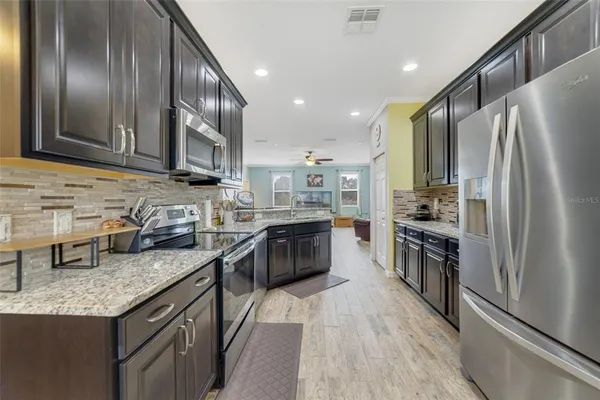 a kitchen with stainless steel appliances granite countertop a refrigerator a stove top oven a sink and dishwasher