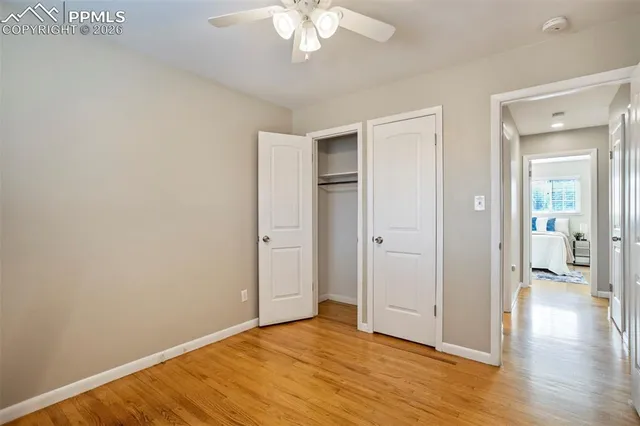 an empty room with wooden floor and a ceiling fan