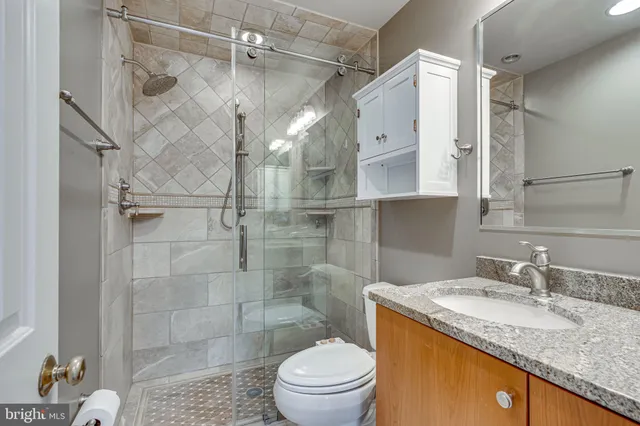 a bathroom with a granite countertop sink toilet and shower