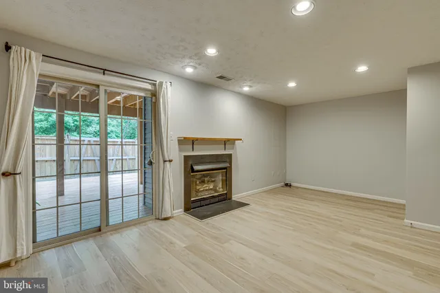 an empty room with wooden floor fireplace and windows