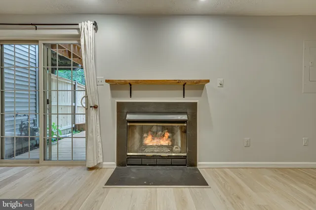 an empty room with wooden floor fireplace and windows