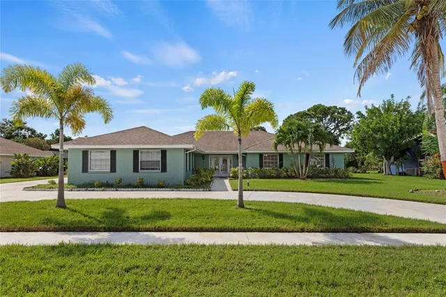 a front view of a house with a yard and palm trees