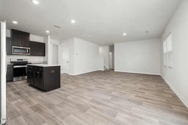 a large kitchen with stainless steel appliances granite countertop a large counter top and a stove with wooden floor