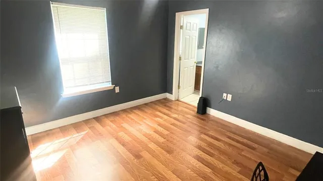a view of an empty room with wooden floor and a window