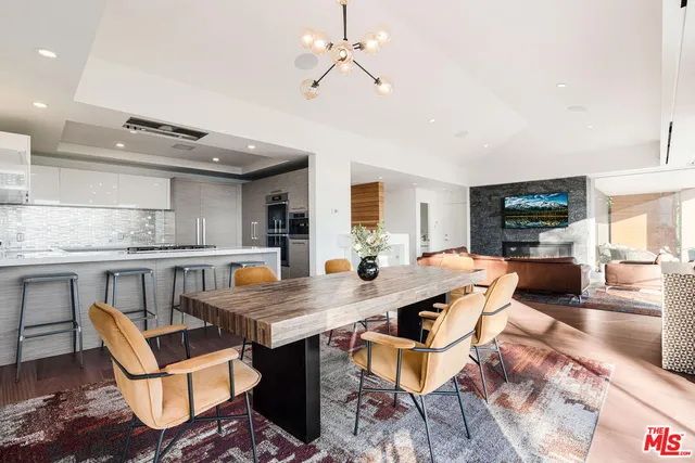 a view of a dining room and livingroom with furniture wooden floor a chandelier