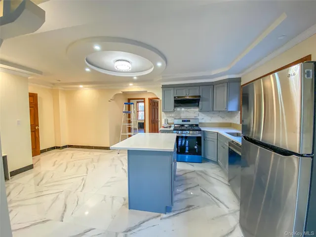 a kitchen with stainless steel appliances kitchen island granite countertop a refrigerator and a stove top oven