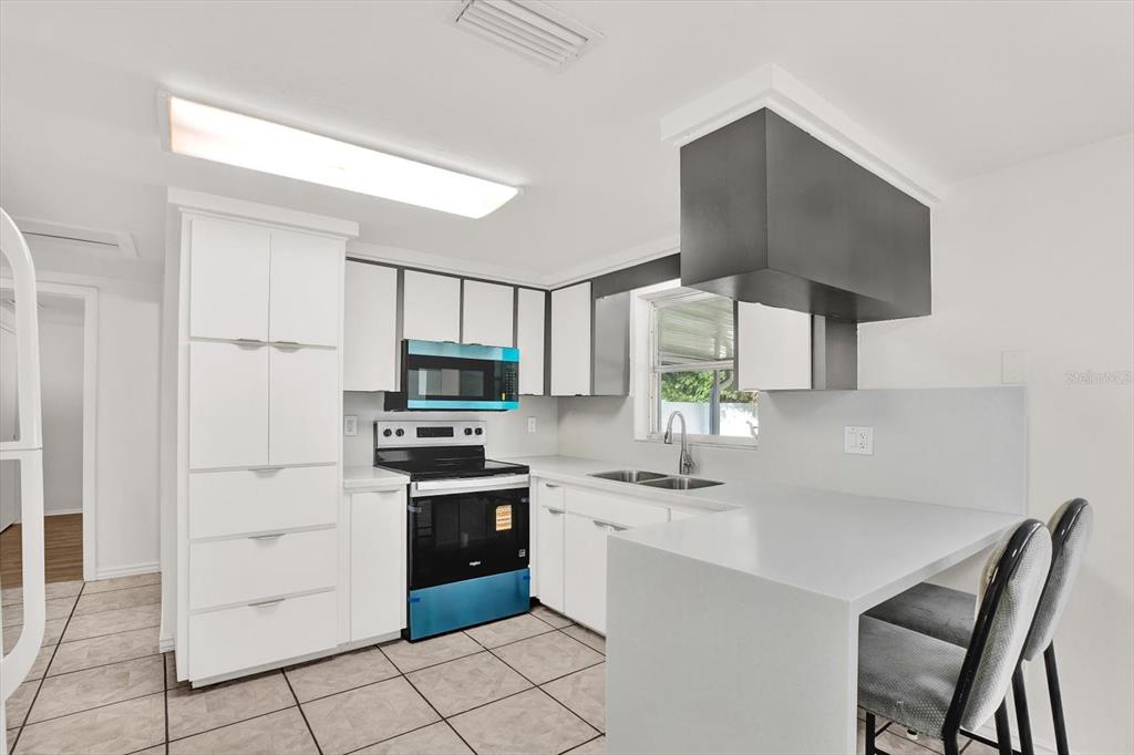 6701 Parkside Drive New Port Richey, FL 34653 - Photo 5 of 26 a kitchen with stainless steel appliances a sink a stove a refrigerator cabinets and a counter top space