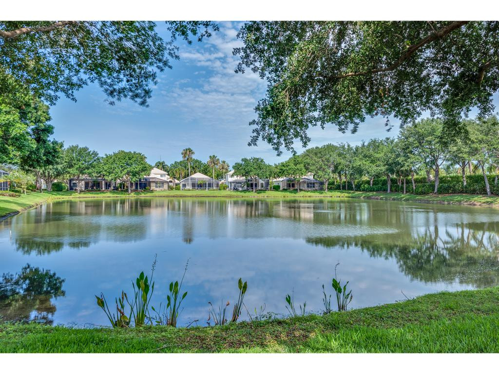 2011 Timarron Way Naples, FL 34109 - Photo 2 of 18 a view of a lake with a yard and trees in the background