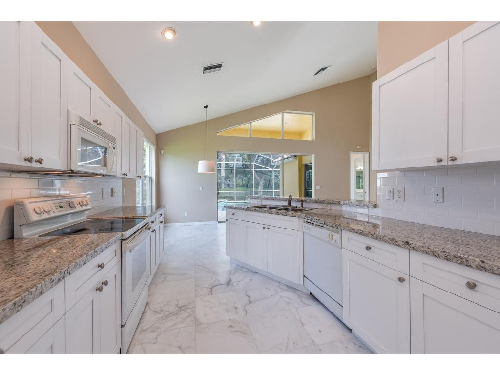 2011 Timarron Way Naples, FL 34109 - Photo 8 of 18 a large kitchen with granite countertop a sink and white cabinets