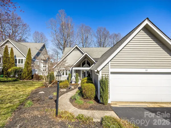 a view of a white house with a small yard and large tree