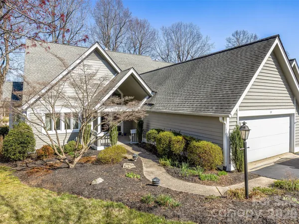a view of a house with large trees and a yard