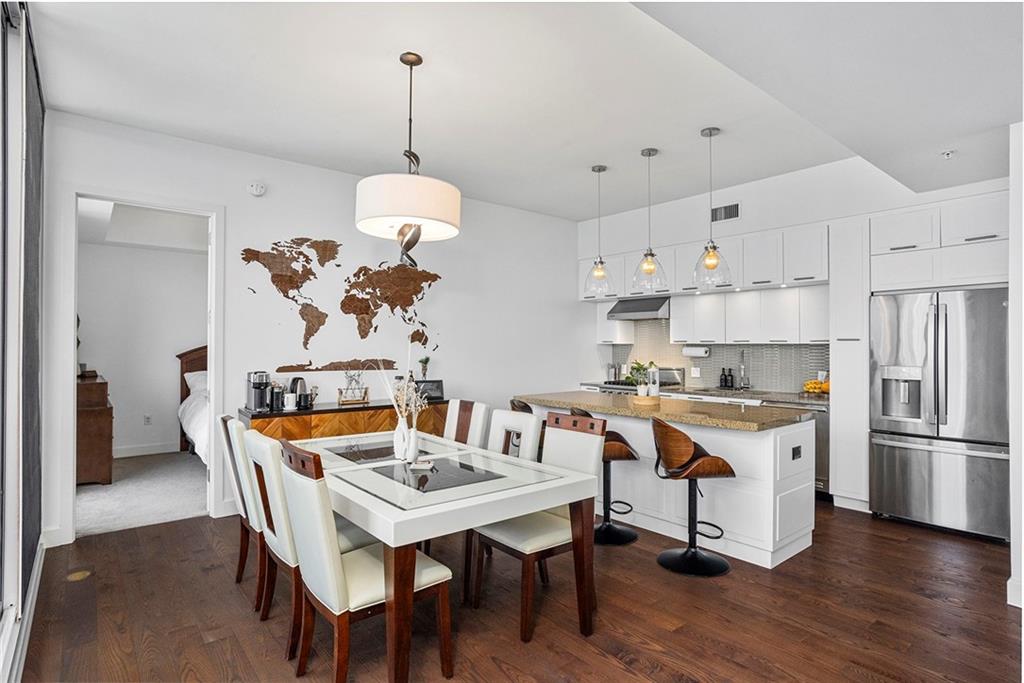 1820 Peachtree Road Northwest, Unit 1509 Atlanta, GA 30309 - Photo 13 of 61 a kitchen with stainless steel appliances granite countertop a dining table and chairs a refrigerator with wooden floors