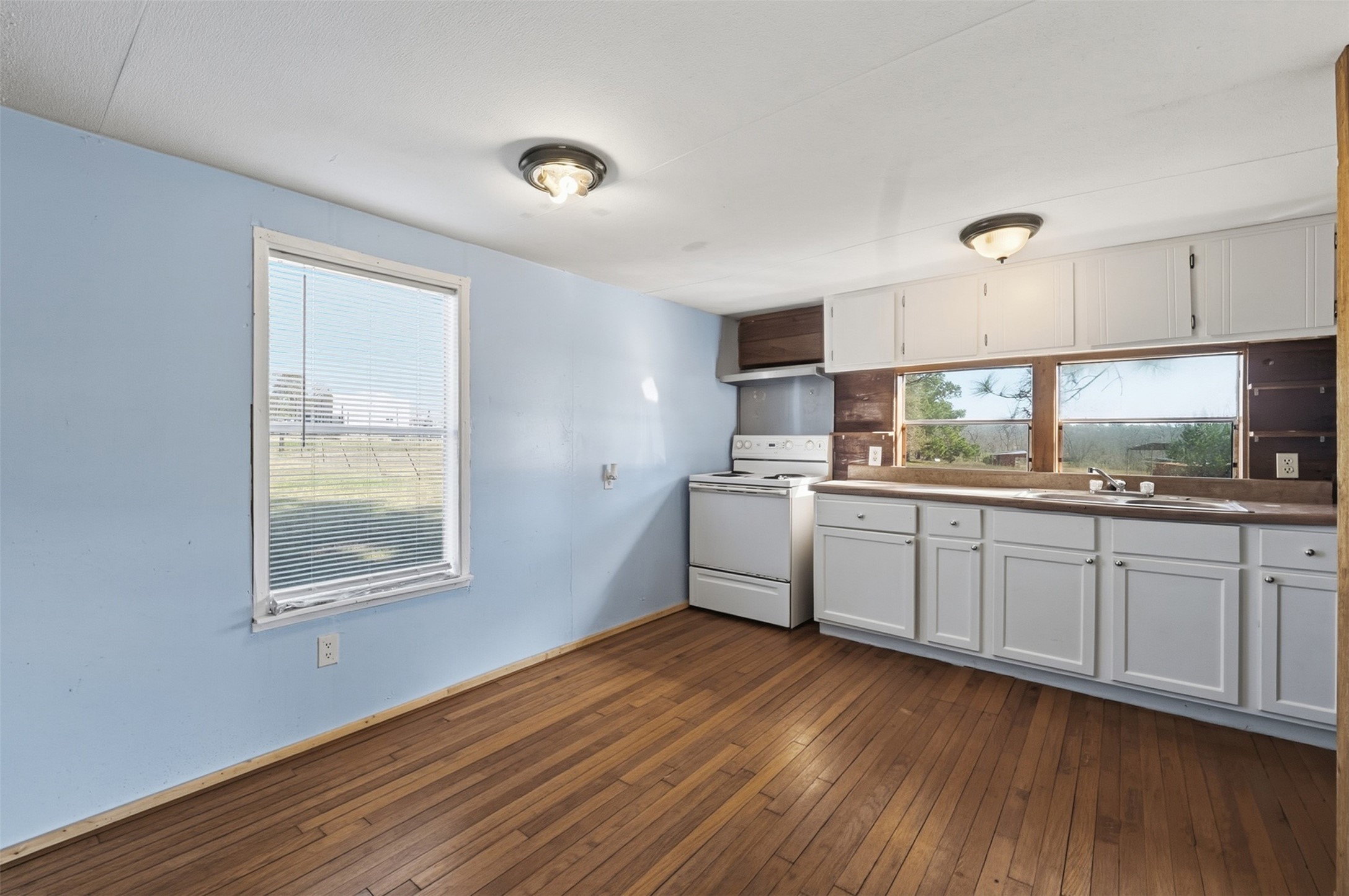 4027 Spring Branch Road Montgomery, TX 77316 - Photo 24 of 32 a kitchen with granite countertop wooden floors white cabinets and window