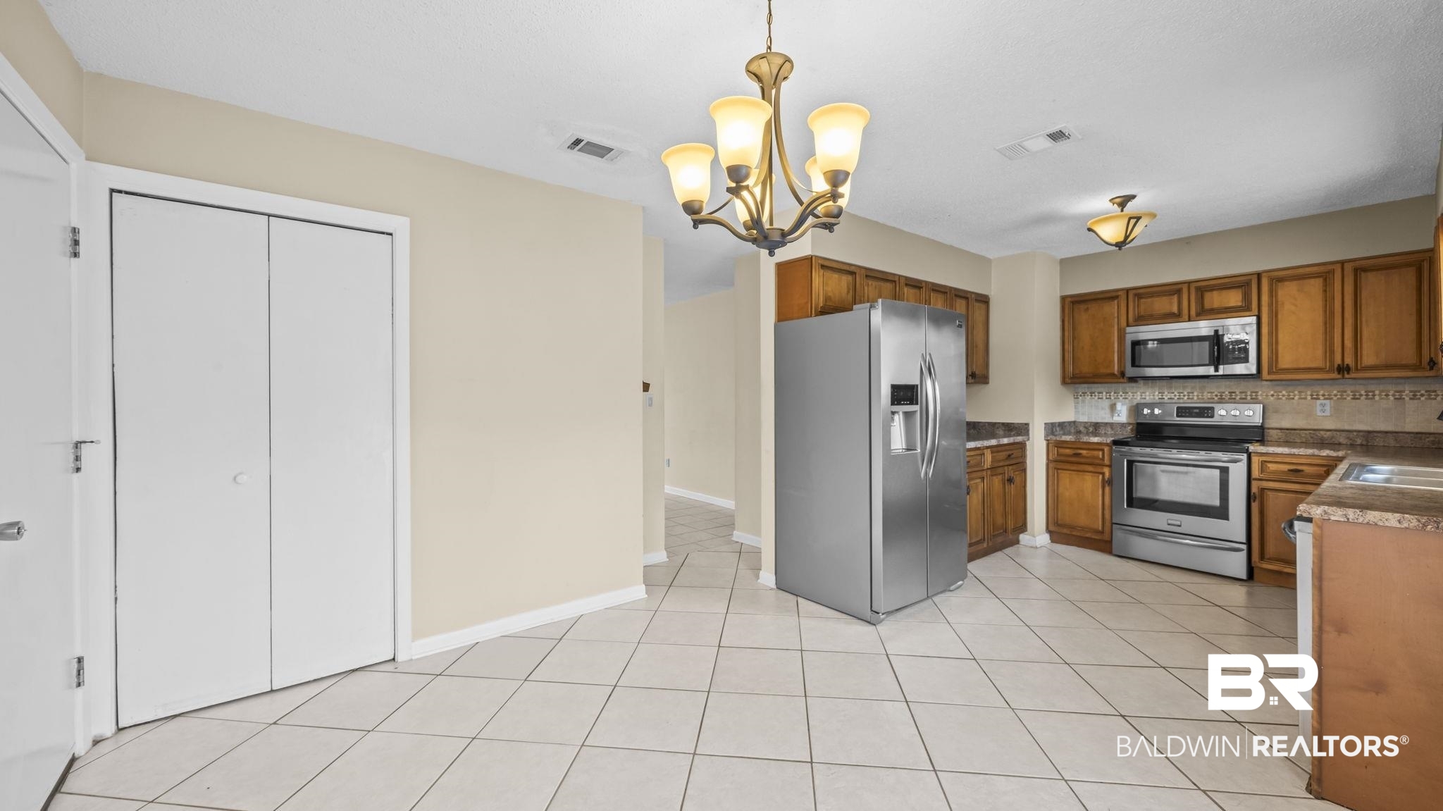 15096 Highland Circle Foley, AL 36535 - Photo 16 of 52 Open-concept kitchen featuring tile flooring, wood cabinetry, stainless steel appliances, and a decorative chandelier