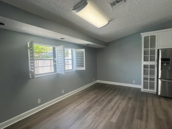 an empty room with wooden floor and a ceiling fan