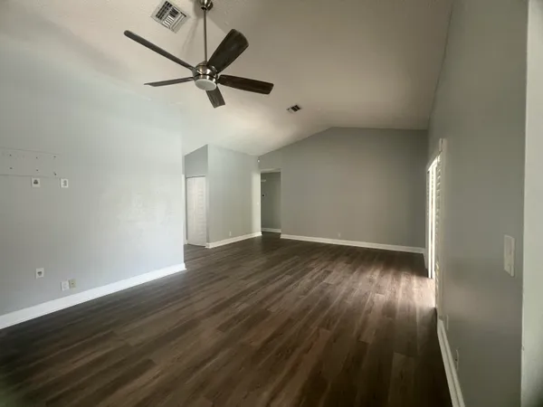 an empty room with wooden floor and windows