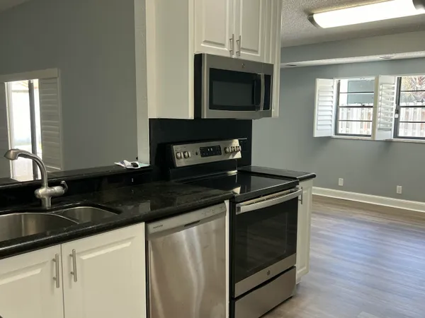 a kitchen with granite countertop a stove microwave and sink