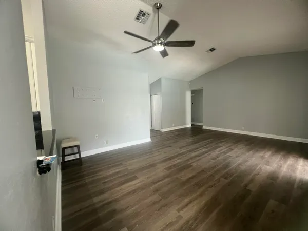 an empty room with wooden floor and a ceiling fan