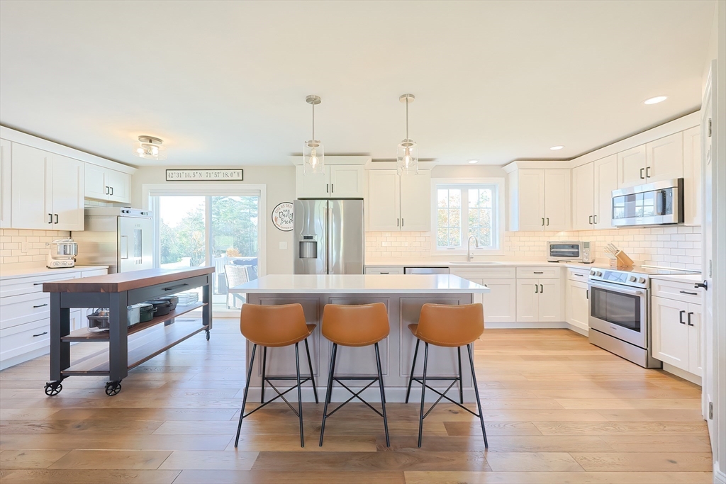 11 Lighthouse Lane Westminster, MA 01473 - Photo 4 of 42 a kitchen with stainless steel appliances kitchen island granite countertop a stove a sink a dining table and chairs with wooden floor