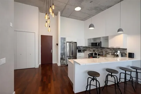 a kitchen with stainless steel appliances a dining table chairs and wooden floor