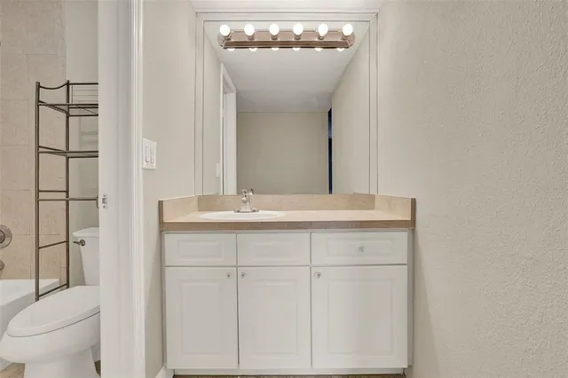 a bathroom with a granite countertop sink a toilet and shower