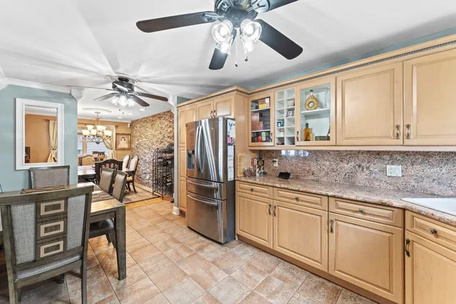 a kitchen with granite countertop a center island a refrigerator cabinets and stainless steel appliances