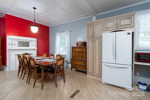 a kitchen with a refrigerator a sink dishwasher a dining table and chairs with wooden floor