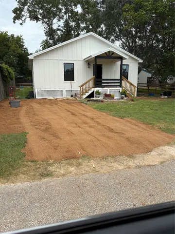 a front view of house with yard and trees in the background