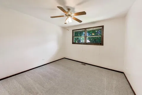 an empty room with a ceiling fan and a window