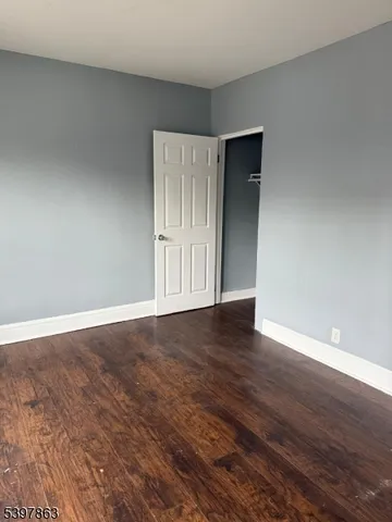 a view of an empty room with wooden floor and closet
