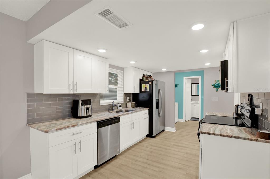 6414 Indiana Avenue New Port Richey, FL 34653 - Photo 5 of 31 a kitchen with granite countertop a sink stainless steel appliances and white cabinets