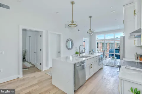a large white kitchen with a large window a sink and cabinets