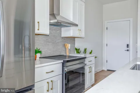 a kitchen with stainless steel appliances white cabinets stove and wooden floor