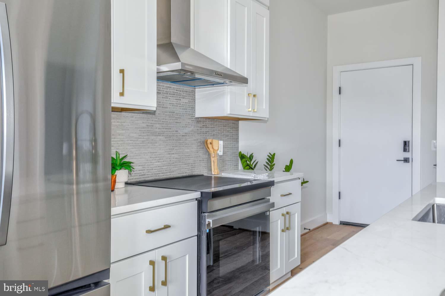 4347 Harrison Street Northwest, Unit 4 Washington, DC 20015 - Photo 8 of 18 a kitchen with stainless steel appliances white cabinets stove and wooden floor