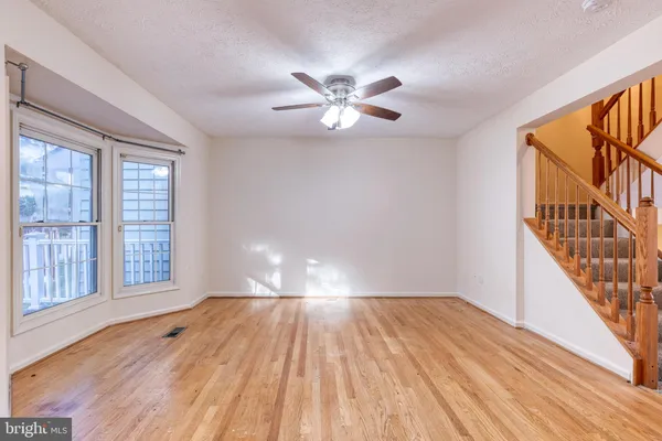 a view of empty room with wooden floor and fan