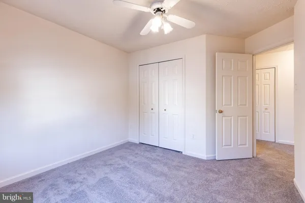 an empty room with closet and fan