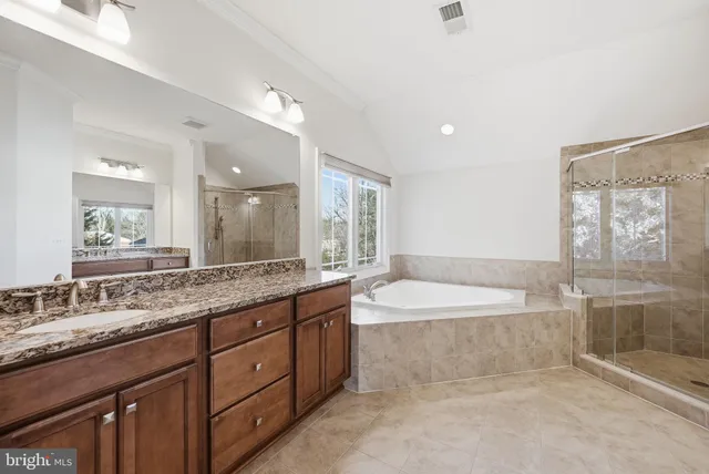 a spacious bathroom with a granite countertop tub double vanity and a mirror