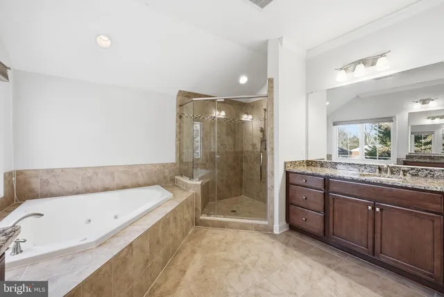 a bathroom with a granite countertop tub a sink and a large mirror